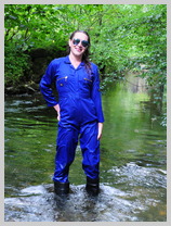  Lucia wades deep into the river in a boilersuits and boots featuring Lucia, The Office Manager 
